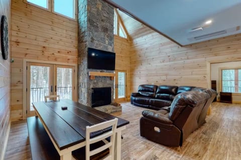 Spacious great room with vaulted ceilings, a floor-to-ceiling stone fireplace, large windows, and comfortable seating for gathering and relaxing.