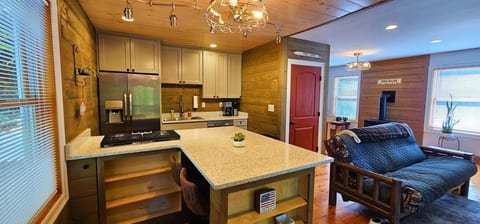 Modern kitchen with a large island, stainless steel appliances, and open-concept living space with rustic wood accents.