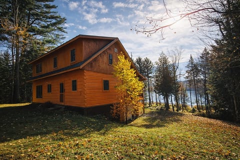 Secluded lakeview cabin surrounded by towering pines and colorful fall foliage, offering a peaceful wooded setting just steps from the water.