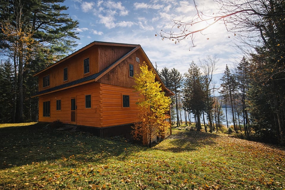 Secluded lakeview cabin surrounded by towering pines and colorful fall foliage, offering a peaceful wooded setting just steps from the water.