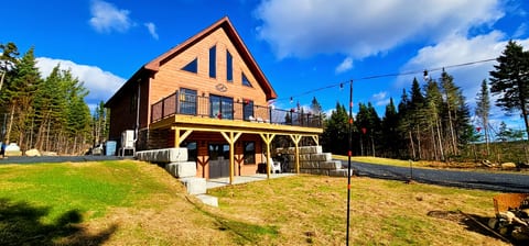 Modern log cabin with a spacious deck, outdoor seating, and scenic forest views.