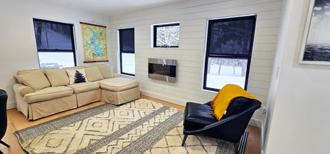 Cozy living room with a comfortable sectional, modern fireplace, and large windows overlooking the surrounding woods for a relaxing retreat atmosphere.