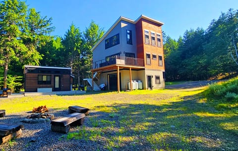 Modern woodland retreat with a spacious deck, private fire pit, and separate guest cabin, surrounded by peaceful forest views and outdoor adventure.
