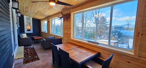 Covered porch with comfortable seating, outdoor dining space, and beautiful mountain views, perfect for relaxing year-round.