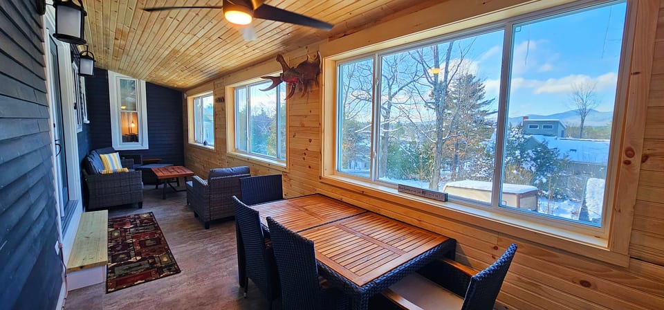 Covered porch with comfortable seating, outdoor dining space, and beautiful mountain views, perfect for relaxing year-round.