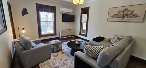 Cozy living room with comfortable seating, a smart TV, and large windows that fill the space with natural light for a relaxing stay.