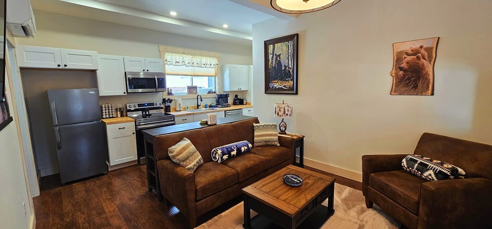 Open-concept living area with a fully equipped kitchen, comfortable leather seating, rustic wildlife décor, and modern amenities for a relaxing cabin stay.