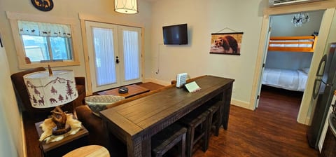Cozy living area with bar-style seating, comfortable furnishings, smart TV, and easy access to the outdoor patio and bunk bedroom.