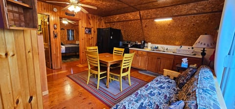Cozy cabin-style living space with a kitchenette, dining table, futon, and warm wood finishes for a comfortable stay.