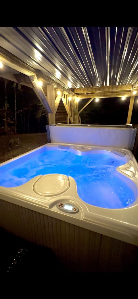 Covered outdoor hot tub with string lights and peaceful forest views for relaxing after a day of adventure.