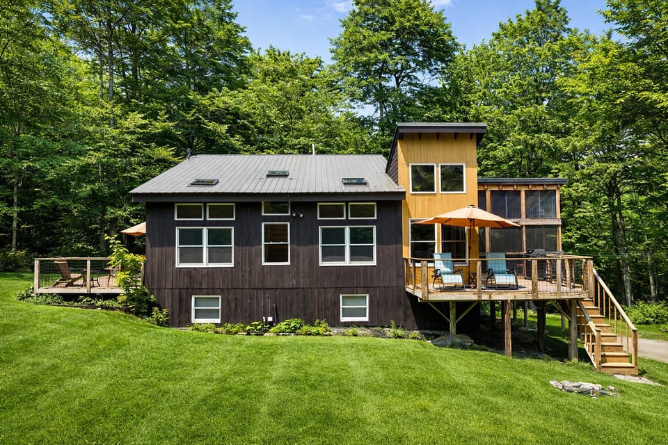 Modern cabin retreat with a spacious deck, outdoor seating, and peaceful forest surroundings.