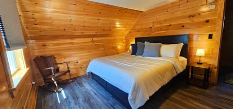 Cozy king bedroom with warm wood accents, comfortable furnishings, and a peaceful cabin atmosphere.
