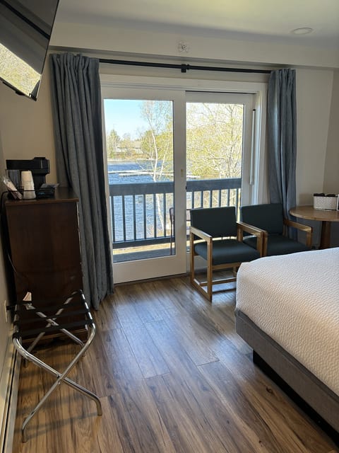 Modern king bedroom with waterfront balcony access, cozy seating, and beautiful lake views right outside your door.