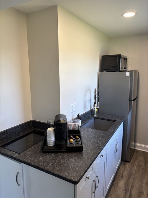 Modern kitchenette with a refrigerator, microwave, cooktop, sink, and Nespresso coffee maker for added convenience during your stay.