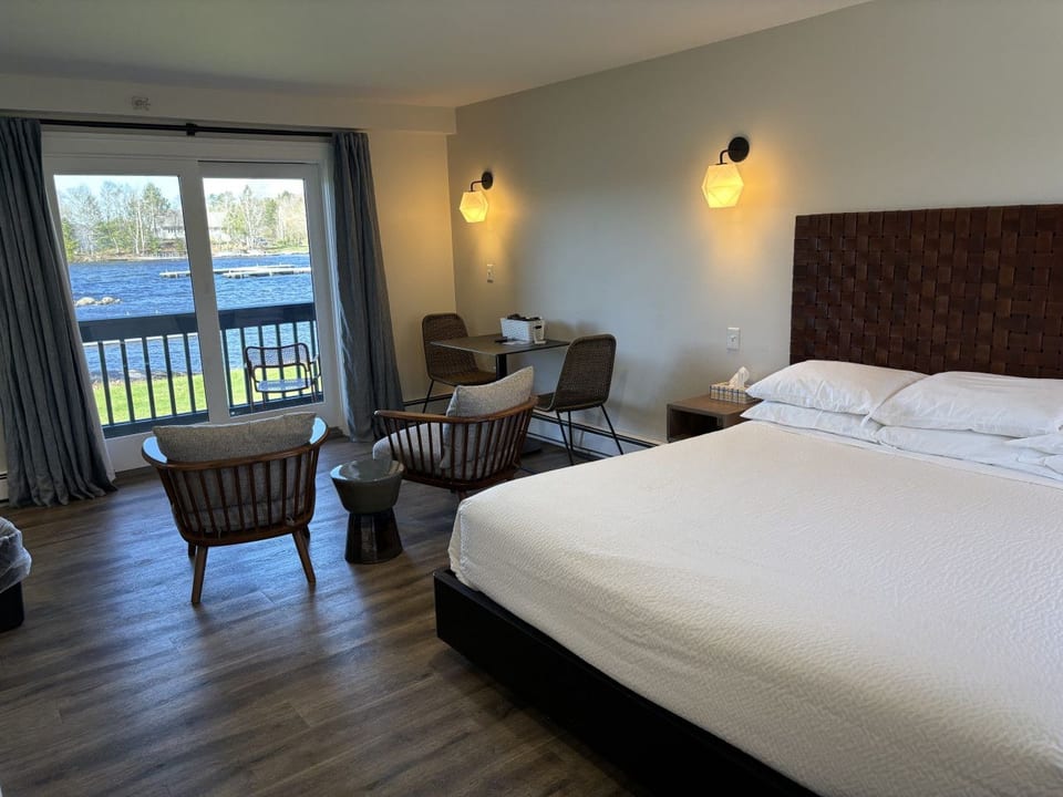 Spacious king bedroom with waterfront views, private balcony access, and cozy seating for relaxing by the lake.