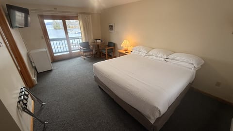 Spacious king bedroom with a private waterfront balcony, comfortable seating area, and beautiful lake views for a relaxing stay.