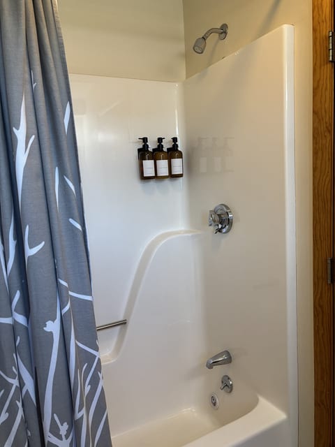 Clean bathroom with a shower-tub combination, fresh towels, and complimentary toiletries for a comfortable stay.