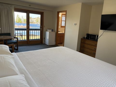 Spacious king bedroom with waterfront views, comfortable seating, and a private balcony overlooking the lake.