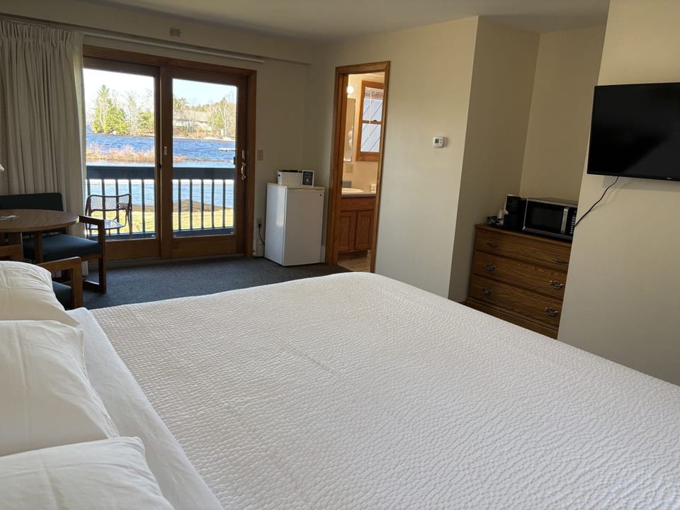 Spacious king bedroom with waterfront views, comfortable seating, and a private balcony overlooking the lake.