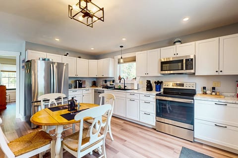 Modern lakeside kitchen with stainless steel appliances, spacious countertops, and a cozy dining area for gathering and meals together.