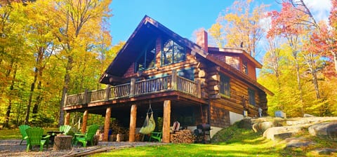 Stunning log cabin retreat with a spacious deck, outdoor fire pit, and beautiful fall foliage views.