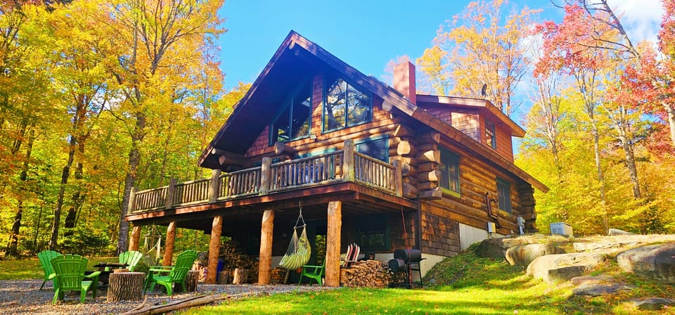Stunning log cabin retreat with a spacious deck, outdoor fire pit, and beautiful fall foliage views.