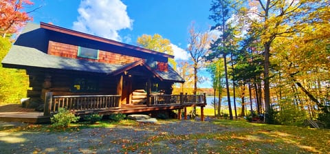 Beautiful waterfront log cabin surrounded by colorful fall foliage with peaceful lake views and a private deck.