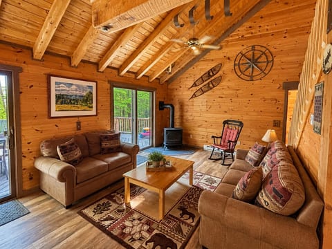 Rustic open-concept living area with vaulted wood ceilings, private deck access, and cozy cabin seating.