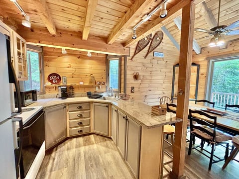 Rustic cabin kitchen with granite countertops, breakfast bar, and open dining area perfect for gathering.