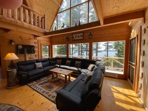 Stunning lakefront great room with soaring cathedral ceilings, floor-to-ceiling windows, and breathtaking water views that bring the outdoors inside.