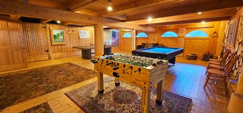 Spacious game room featuring a pool table, foosball, ping pong, and comfortable lounge space for endless family fun and friendly competition.