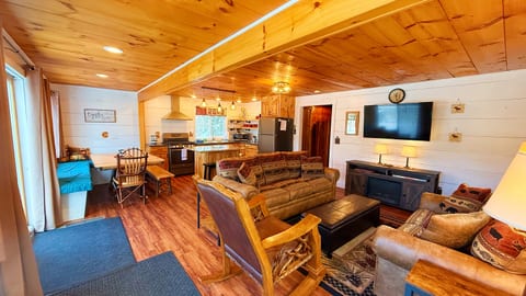 Spacious open-concept cabin living area with rustic furnishings, a fully equipped kitchen, and comfortable seating for memorable family gatherings.