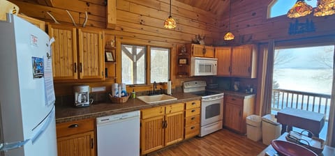 Rustic lakefront kitchen with warm wood cabinetry, vaulted ceilings.