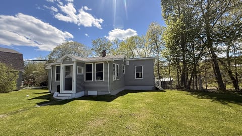Charming cottage retreat with a spacious yard, mature trees, and a peaceful setting for a relaxing getaway.