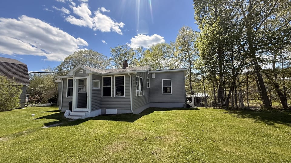 Charming cottage retreat with a spacious yard, mature trees, and a peaceful setting for a relaxing getaway.