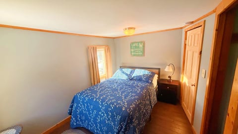 Cozy bedroom with a full bed, warm wood accents, and natural light.
