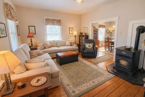 Cozy farmhouse living room with warm wood floors, a wood stove, and inviting rustic charm.
