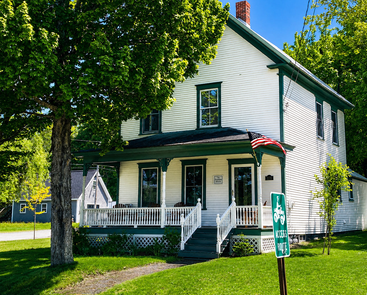 Charming white farmhouse retreat with a wraparound porch, shaded yard, and peaceful small-town setting.