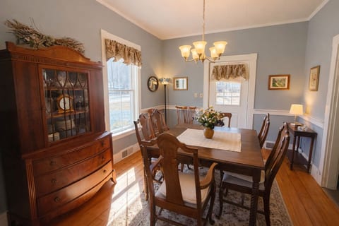 Bright farmhouse dining room with warm wood floors, natural light, and timeless rustic charm.