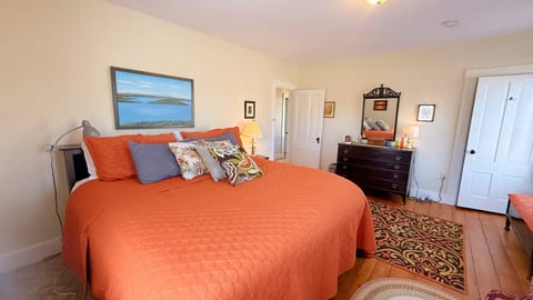 Spacious king bedroom with warm wood floors, cozy decor, and bright natural light.