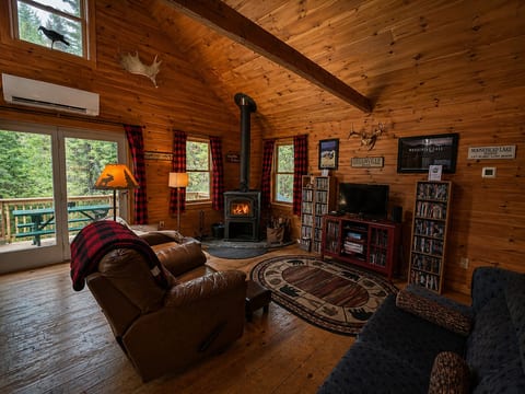 Cozy cabin living room with wood stove, vaulted ceilings, and warm rustic mountain charm.