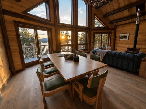 Spacious dining area with large windows showcasing beautiful sunset views over the water.