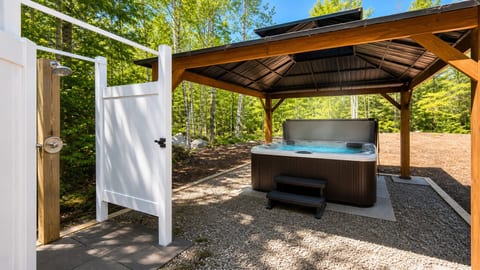 Private hot tub and outdoor shower surrounded by peaceful forest views.