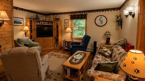 Relax in the cozy living room with comfortable seating, a TV, and warm cabin-style decor.