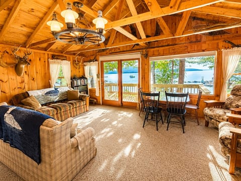Cozy lakefront living room with panoramic water views and rustic wood interior.