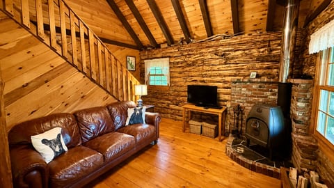 Cozy log cabin living room with a wood stove, comfortable seating, and rustic charm.