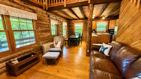 Rustic log cabin living area with comfortable seating, a dining table, and an open-concept layout.