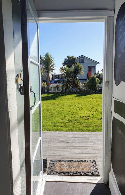 Looking out the back door.  Large grassed backyard and small deck area facing the street and beach. 