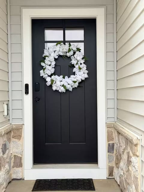 Welcoming entryway with elegant black door and charming floral wreath