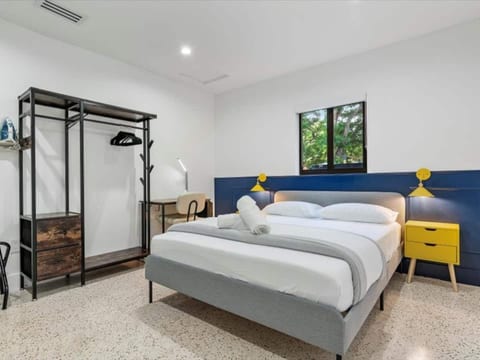 Unique loft-style stay in Miami, Florida, Features a cozy main bed, two lofted singles, minimalist decor, and a sleek workspace—perfect for families or groups exploring vibrant local culture and nearby attractions.